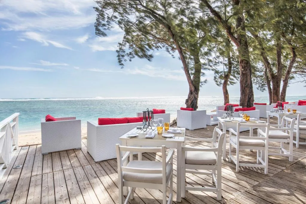 Terrasse du Hotel Lux Restaurant Saint Gilles avec vue sur le lagon, mobilier blanc et coussins roug